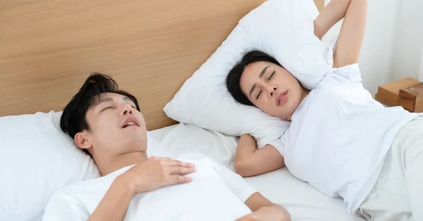 A man snores in bed with a woman. He needs treatment for snoring